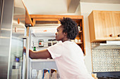 Woman reaching into refrigerator in kitchen