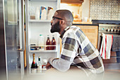 Hungry man peering into refrigerator in kitchen