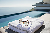 Sunglasses on folded towel at poolside
