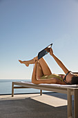 Woman sunbathing, using digital tablet