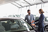 Car saleswoman showing car to customer in showroom