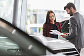 Car saleswoman showing brochure to customer