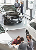 Car sales people and customers in showroom