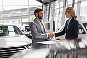 Car saleswoman and customer handshaking