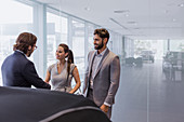 Car salesman greeting couple customers in showroom