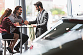 Car salesman handshaking with couple