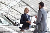 Car saleswoman talking to customer in showroom