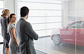 Car sales people looking at new, red car