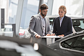 Car salesman and customer reviewing paperwork
