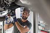 Portrait auto mechanic working under car
