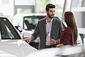 Car salesman showing car to customer in showroom