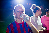 Young soccer player drinking from water bottle