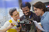 Smiling journalists and cameraman using digital camera