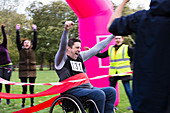 Man in wheelchair crossing race finish line