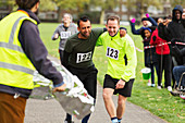 Runner helping injured man running at marathon