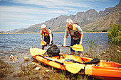 Active senior couple preparing kayak
