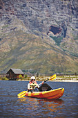 Active senior man kayaking on sunny summer lake