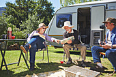 Active senior friends reading outside camper van