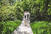 Active senior couple and dog crossing footbridge
