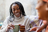 Woman listening to friend and drinking coffee