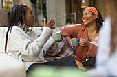 Women talking and drinking coffee on sofa