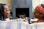 Smiling women friends talking and drinking tea