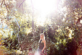 Serene woman standing in sunny summer woods