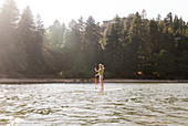 Woman paddleboarding on sunny, tranquil lake
