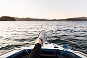 Personal perspective woman boating with feet up