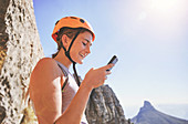 Smiling female rock climber using smart phone