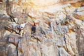 Rock climbers high-fiving on rock wall