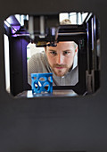 Focused male designer watching 3D printer