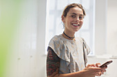 Portrait smiling woman with tattoos texting