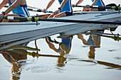 Reflection of female rowers rowing scull on lake