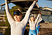 Confident rowing team lifting scull overhead