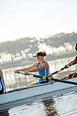 Determined female rower rowing scull on lake