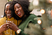 Sisters drinking wine next to Christmas tree