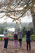 Active seniors practicing yoga in autumn park