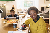 Portrait smiling senior woman paying bills