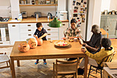 Grandparents watching grandchildren carving pumpkins