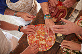 Senior friends adding tomatoes and meat to pizza