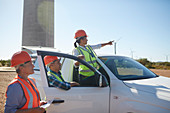 Engineers at truck at sunny wind turbine power plant