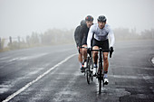 Dedicated male cyclists cycling on rainy road