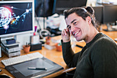 Portrait smiling male graphic designer working at desk