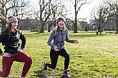 Smiling women doing lunges in sunny park