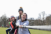 Determined team pulling rope in tug-of-war in park