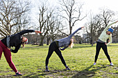 Women runners stretching in sunny park