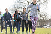 Team cheering woman running in sunny park