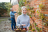 Portrait mature woman harvesting apples in garden