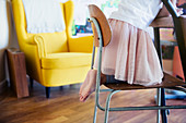 Cute barefoot girl in tutu kneeling on chair